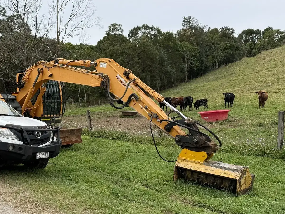 Excavator with a mulcher attachment on a rural property